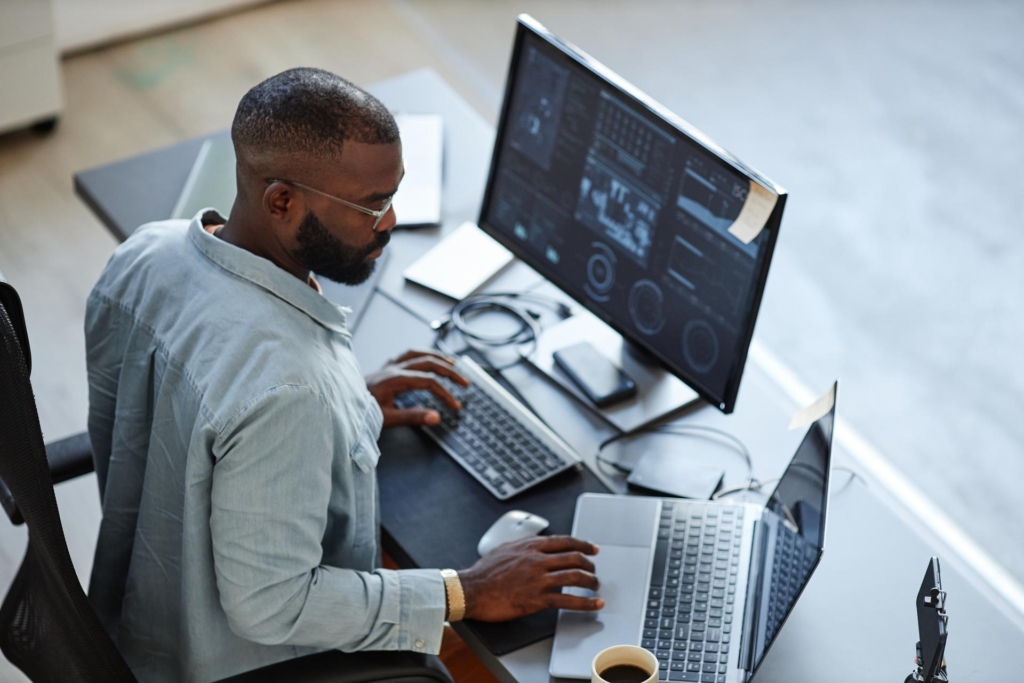 Minimal high angle view at a software developer working with computers and data systems in office